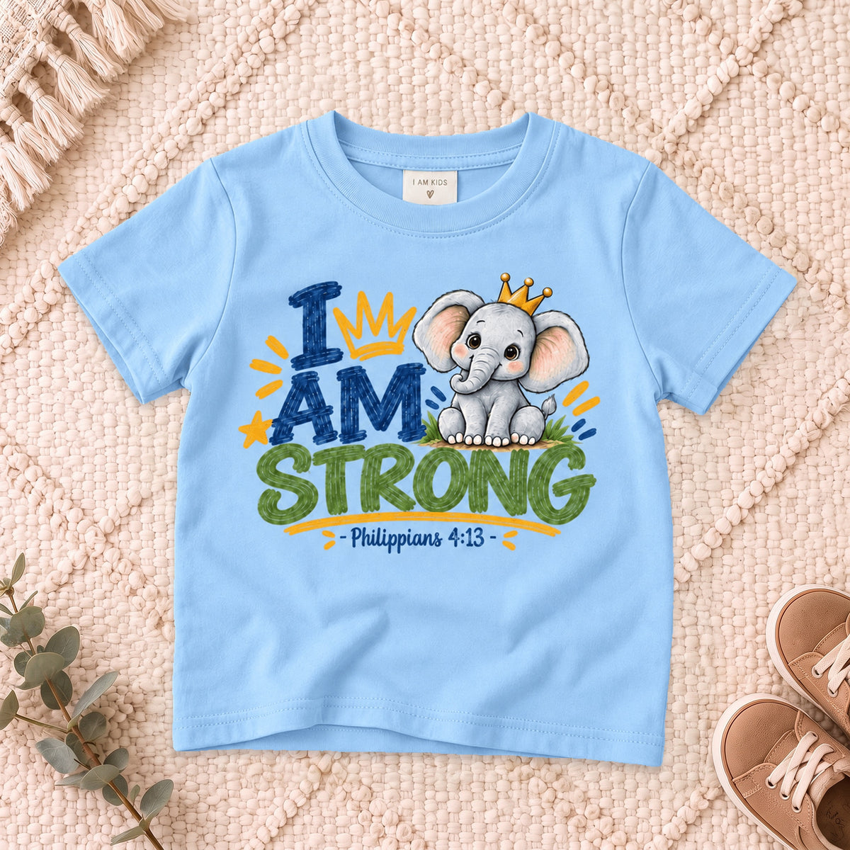 I AM Kids strong design on a Light Blue shirt, shown on a cream rug.