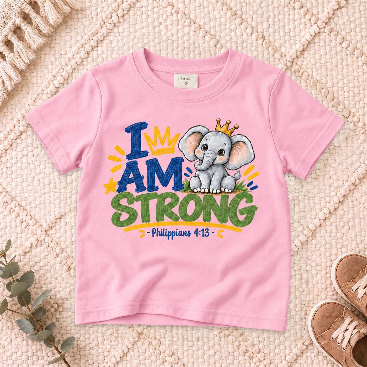I AM Kids strong design on a Light Pink shirt, shown on a cream rug.