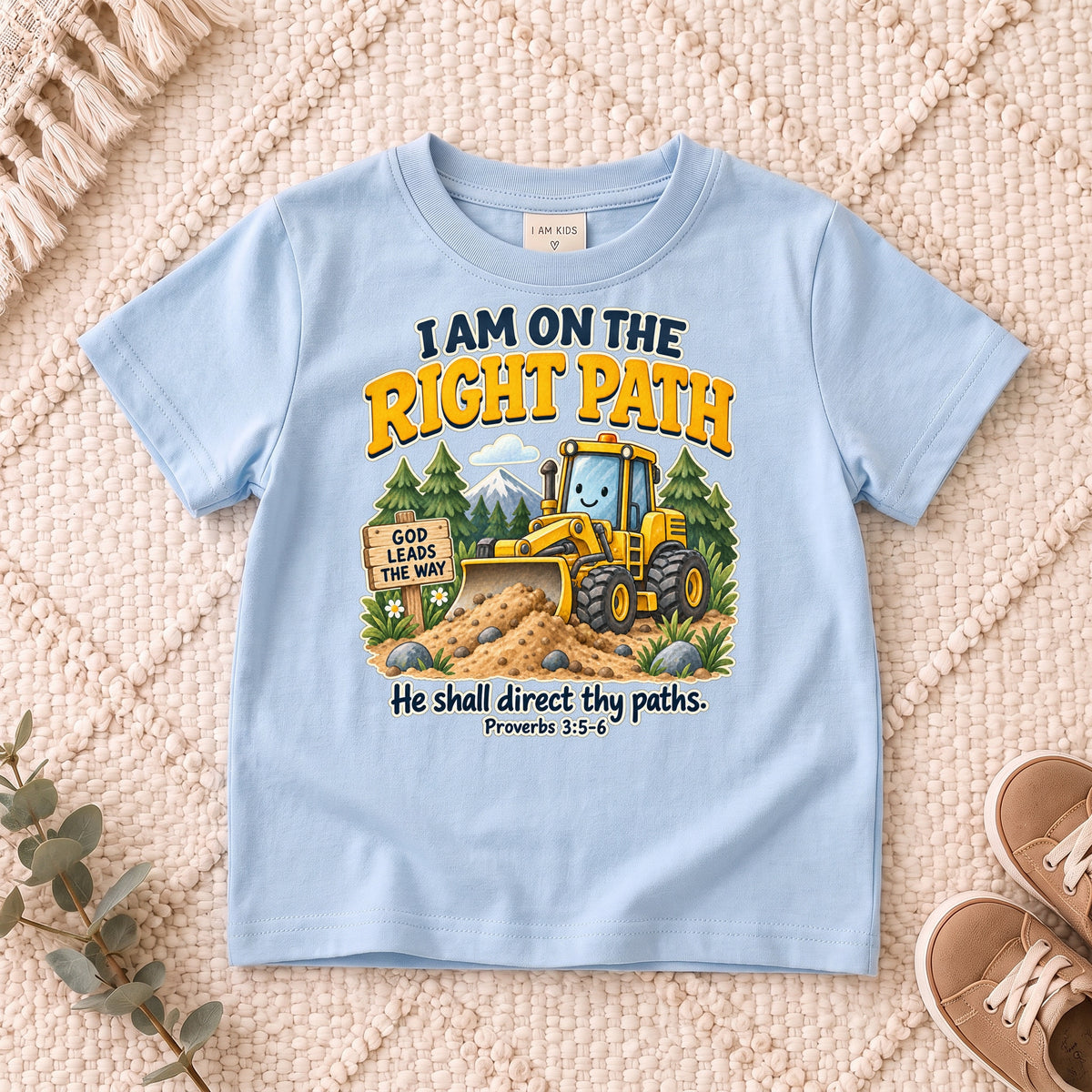 I AM Kids truck path design on a Light Blue shirt, shown on a cream rug.