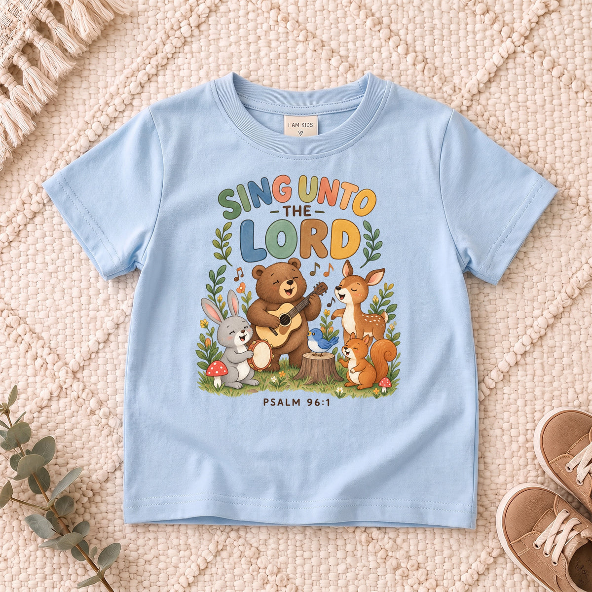 I AM Kids sing bear design on a Light Blue shirt, shown on a cream rug.