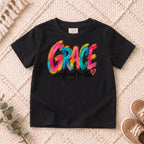 I AM Kids grace design on a Black shirt, shown on a cream rug.