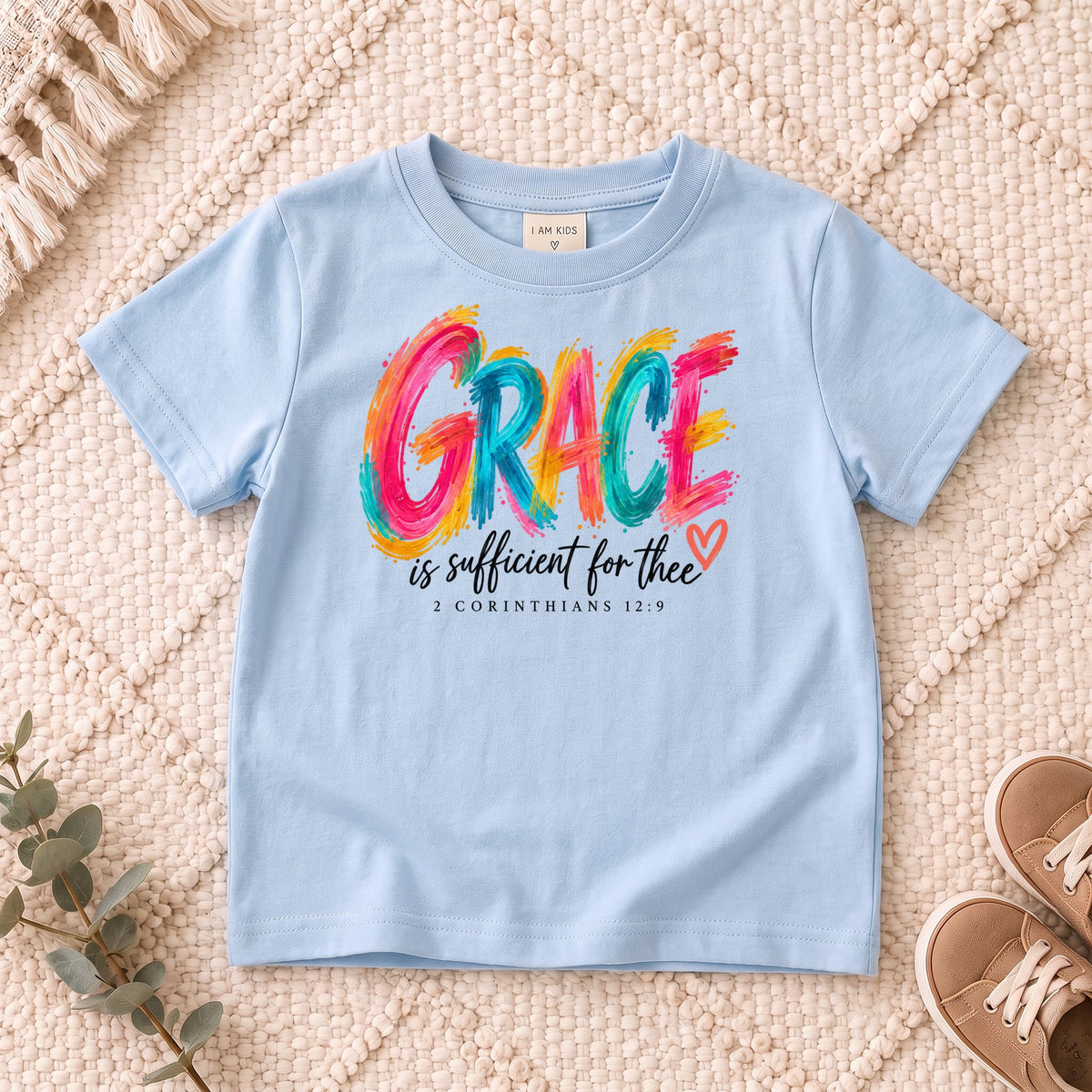 I AM Kids grace design on a Light Blue shirt, shown on a cream rug.