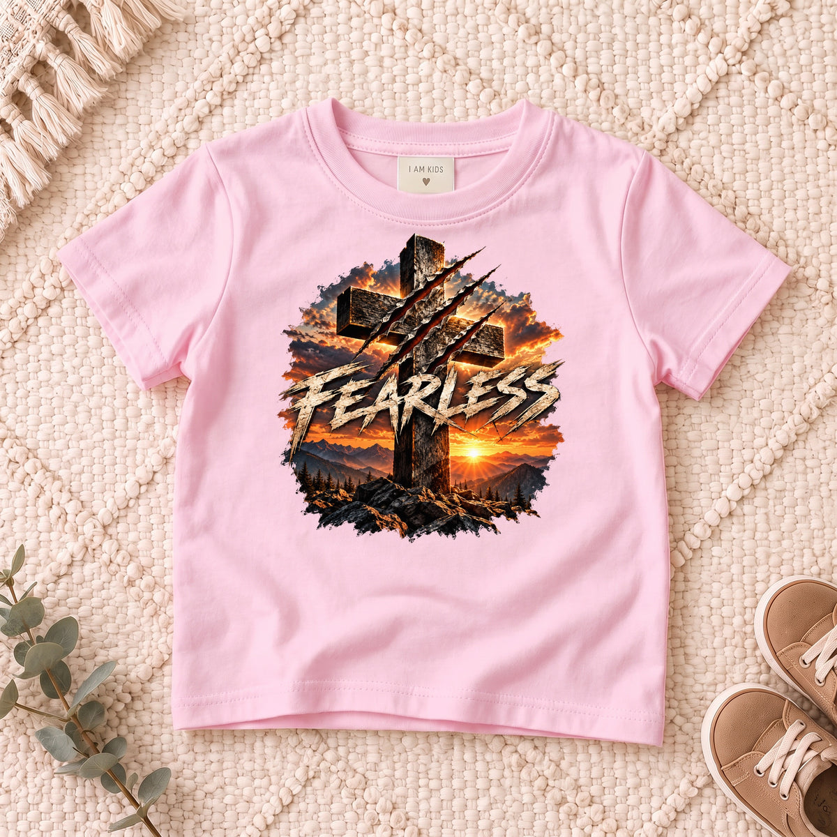 I AM Kids FEARLESS Cross Kids Tee design on a Light Pink shirt, shown on a cream rug.