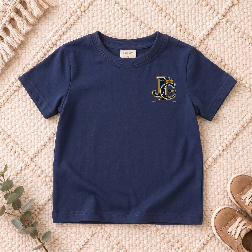 I AM Kids Crowned JC Jesus Christ Kids Tee | Left Chest design on a Navy shirt, shown on a cream rug.