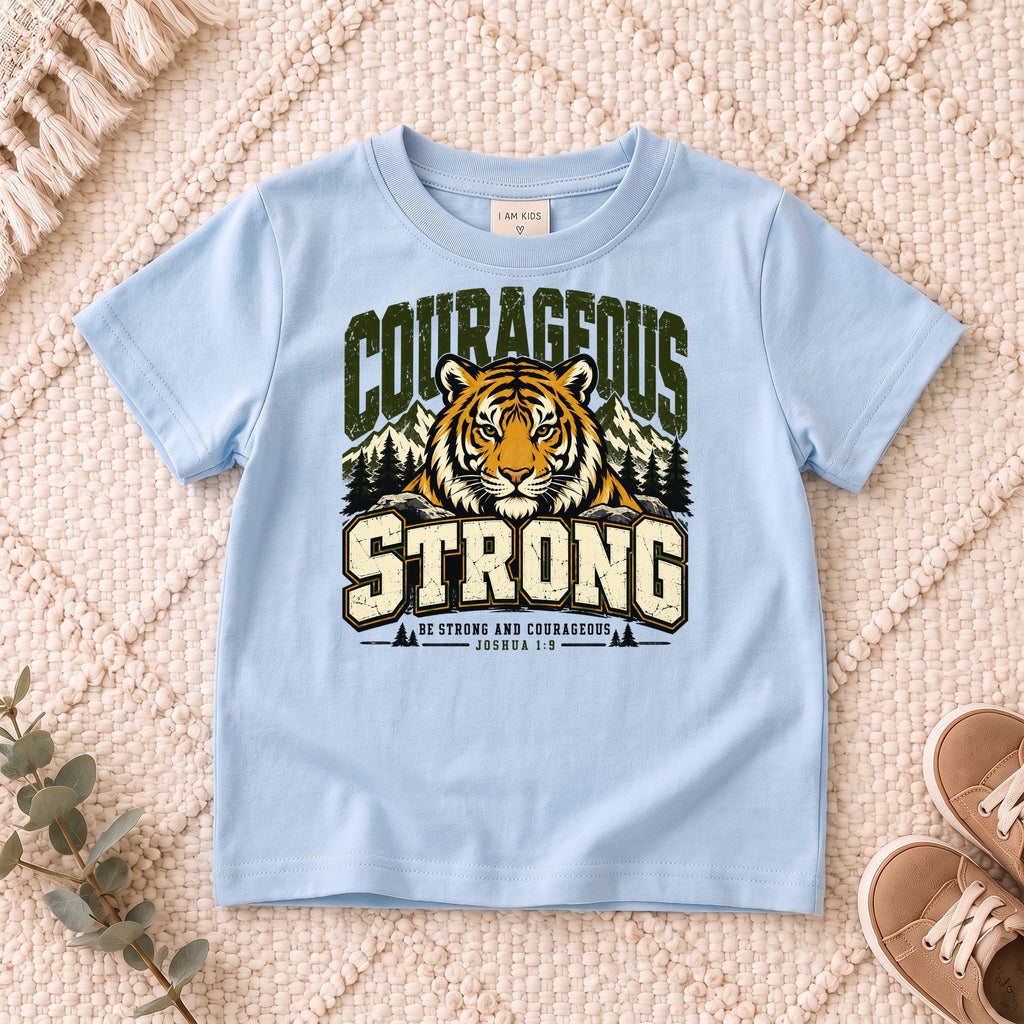 I AM Kids Be Strong & Courageous Tiger Kids Tee design on a Light Blue shirt, shown on a cream rug.