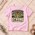 I AM Kids Be Strong & Courageous Tiger Kids Tee design on a Light Pink shirt, shown on a cream rug.