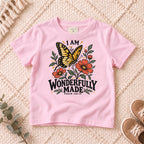 I AM Kids I AM Wonderfully Made Butterfly Kids Tee | Psalm 139:14 design on a Light Pink shirt, shown on a cream rug.
