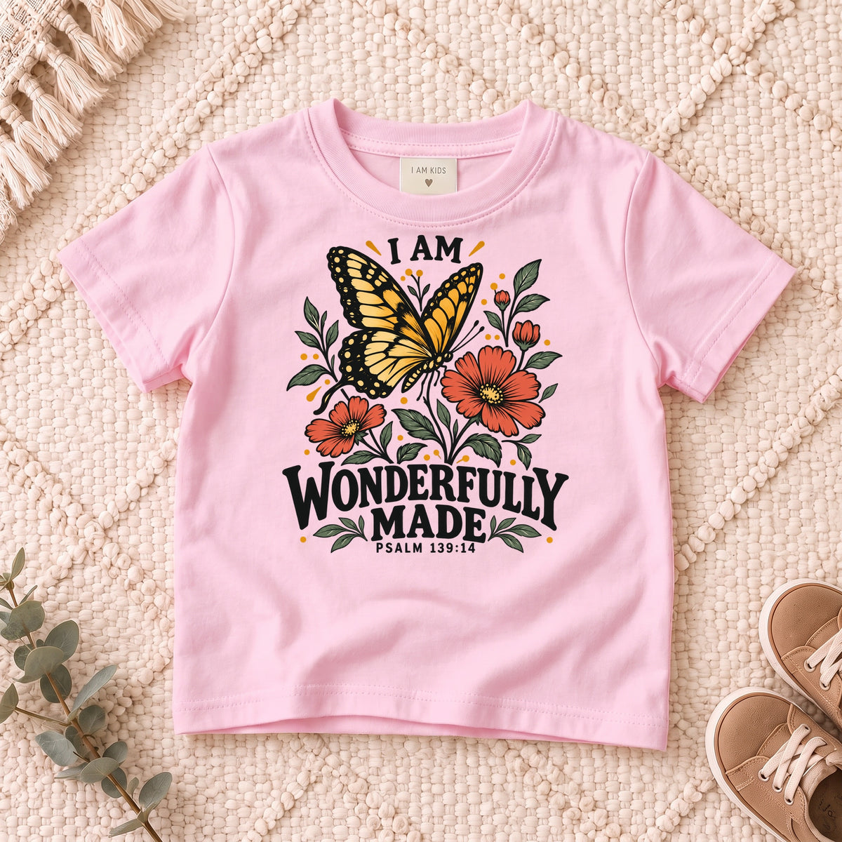 I AM Kids I AM Wonderfully Made Butterfly Kids Tee | Psalm 139:14 design on a Light Pink shirt, shown on a cream rug.