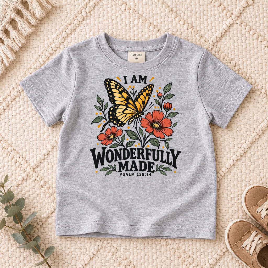 I AM Kids I AM Wonderfully Made Butterfly Kids Tee | Psalm 139:14 design on a Sport Grey shirt, shown on a cream rug.