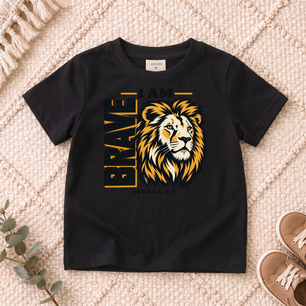 I AM Kids I AM Brave Lion Kids Tee | Joshua 1:9 design on a Black shirt, shown on a cream rug.