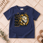 I AM Kids I AM Brave Lion Kids Tee | Joshua 1:9 design on a Navy shirt, shown on a cream rug.