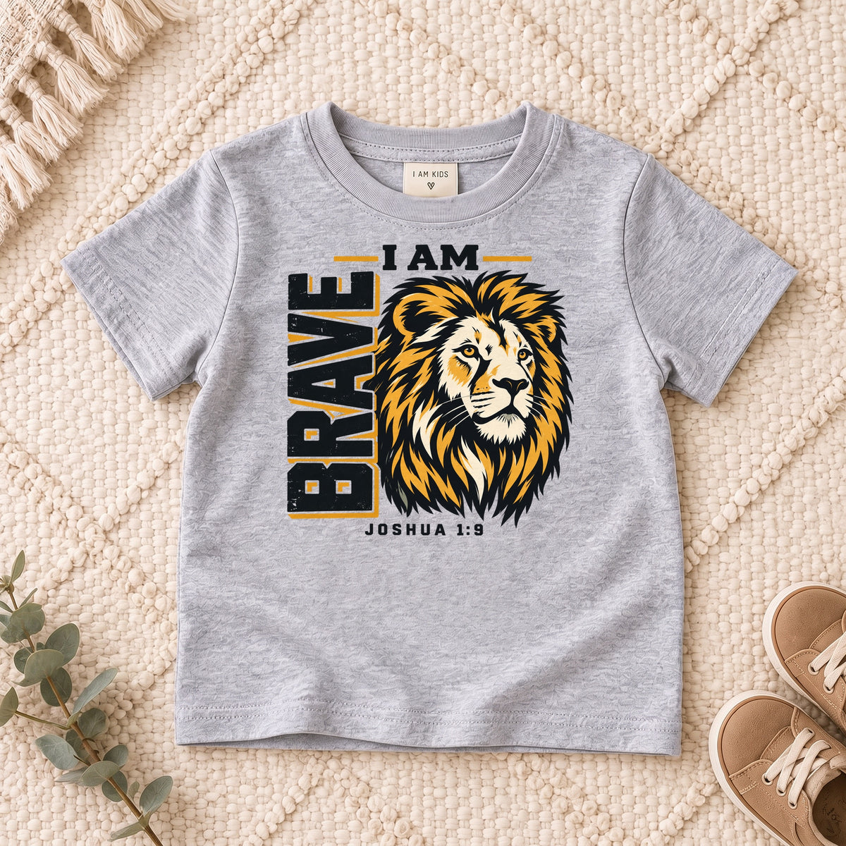 I AM Kids I AM Brave Lion Kids Tee | Joshua 1:9 design on a Sport Grey shirt, shown on a cream rug.