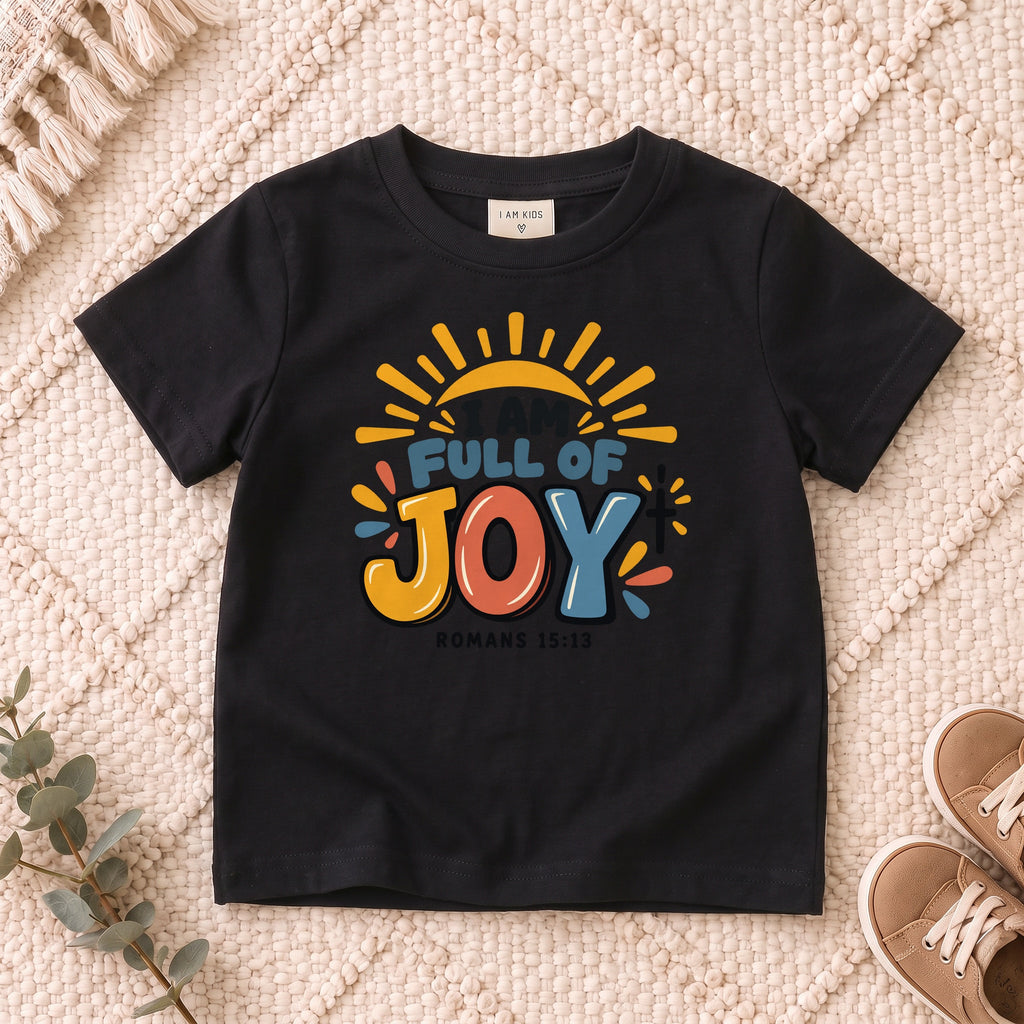 I AM Kids I AM Full of Joy Sunshine Kids Tee | Romans 15:13 design on a Black shirt, shown on a cream rug.