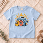 I AM Kids I AM Full of Joy Sunshine Kids Tee | Romans 15:13 design on a Light Blue shirt, shown on a cream rug.