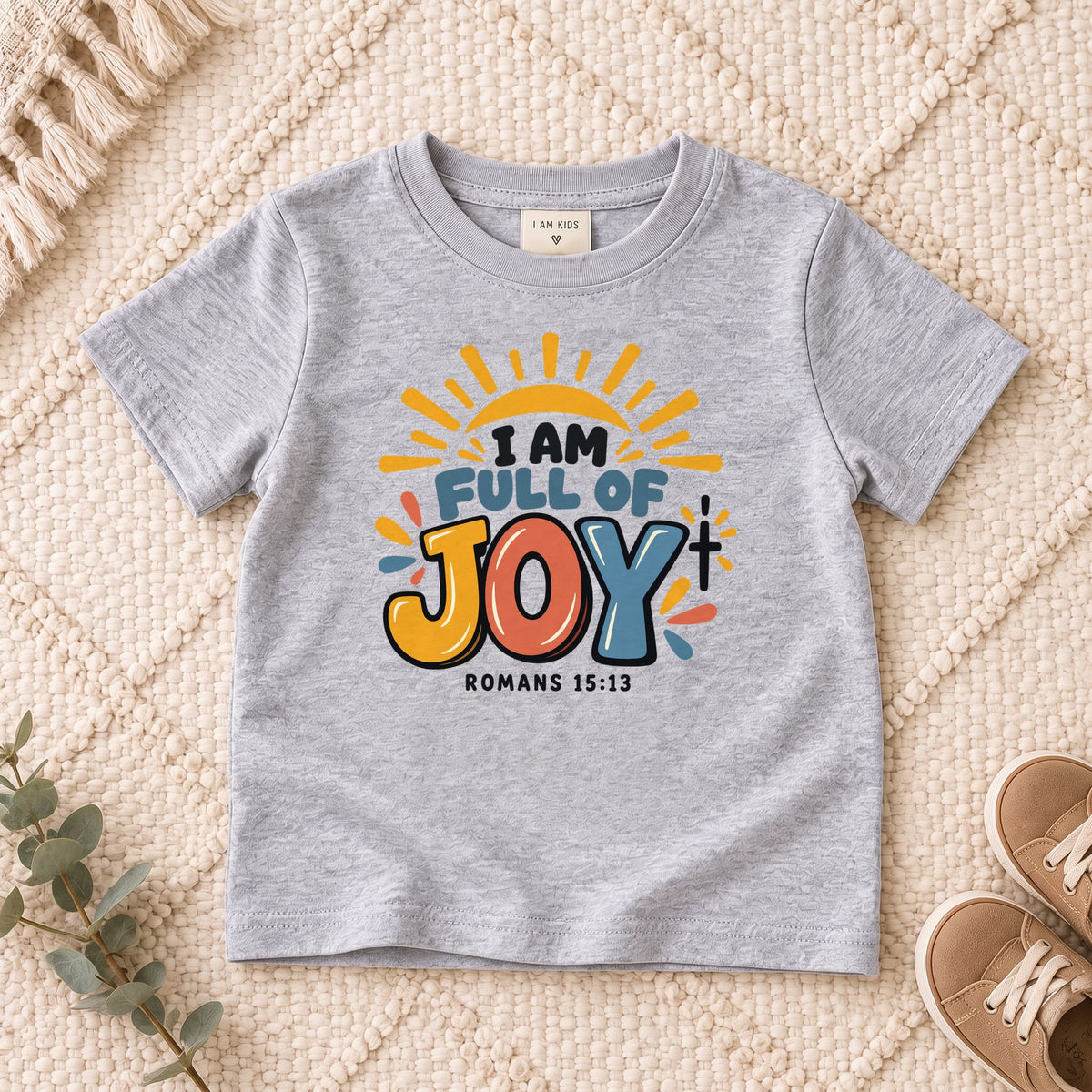 I AM Kids I AM Full of Joy Sunshine Kids Tee | Romans 15:13 design on a Sport Grey shirt, shown on a cream rug.