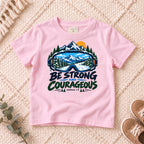 I AM Kids Be Strong & Courageous Mountain Goggles Kids Tee | Joshua 1:9 design on a Light Pink shirt, shown on a cream rug.