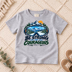 I AM Kids Be Strong & Courageous Mountain Goggles Kids Tee | Joshua 1:9 design on a Sport Grey shirt, shown on a cream rug.