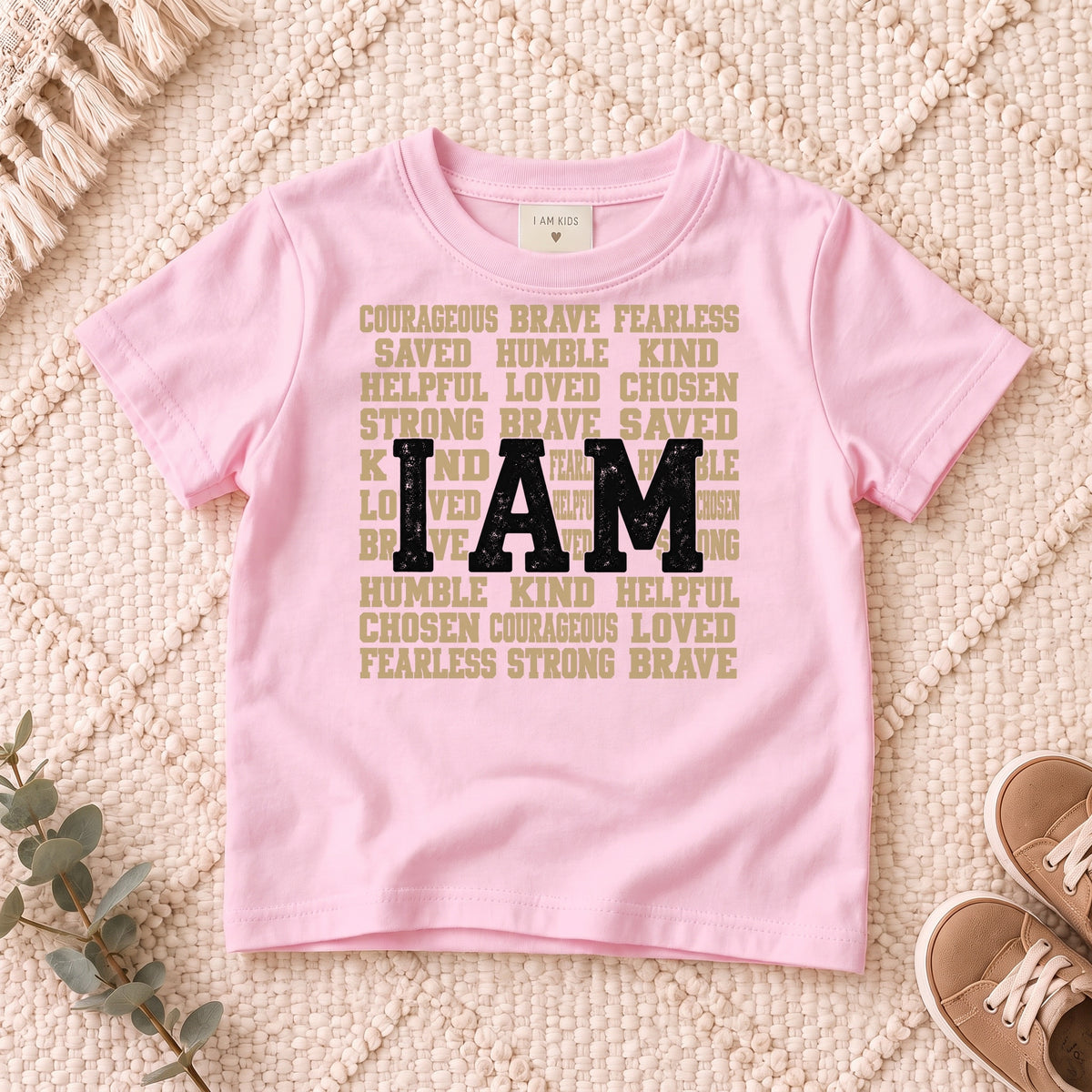 I AM Kids I AM Words of Faith Kids Tee design on a Light Pink shirt, shown on a cream rug.