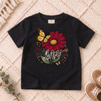 I AM Kids I AM Loved & Chosen Burgundy Flower Kids Tee | Psalm 139:14 design on a Black shirt, shown on a cream rug.