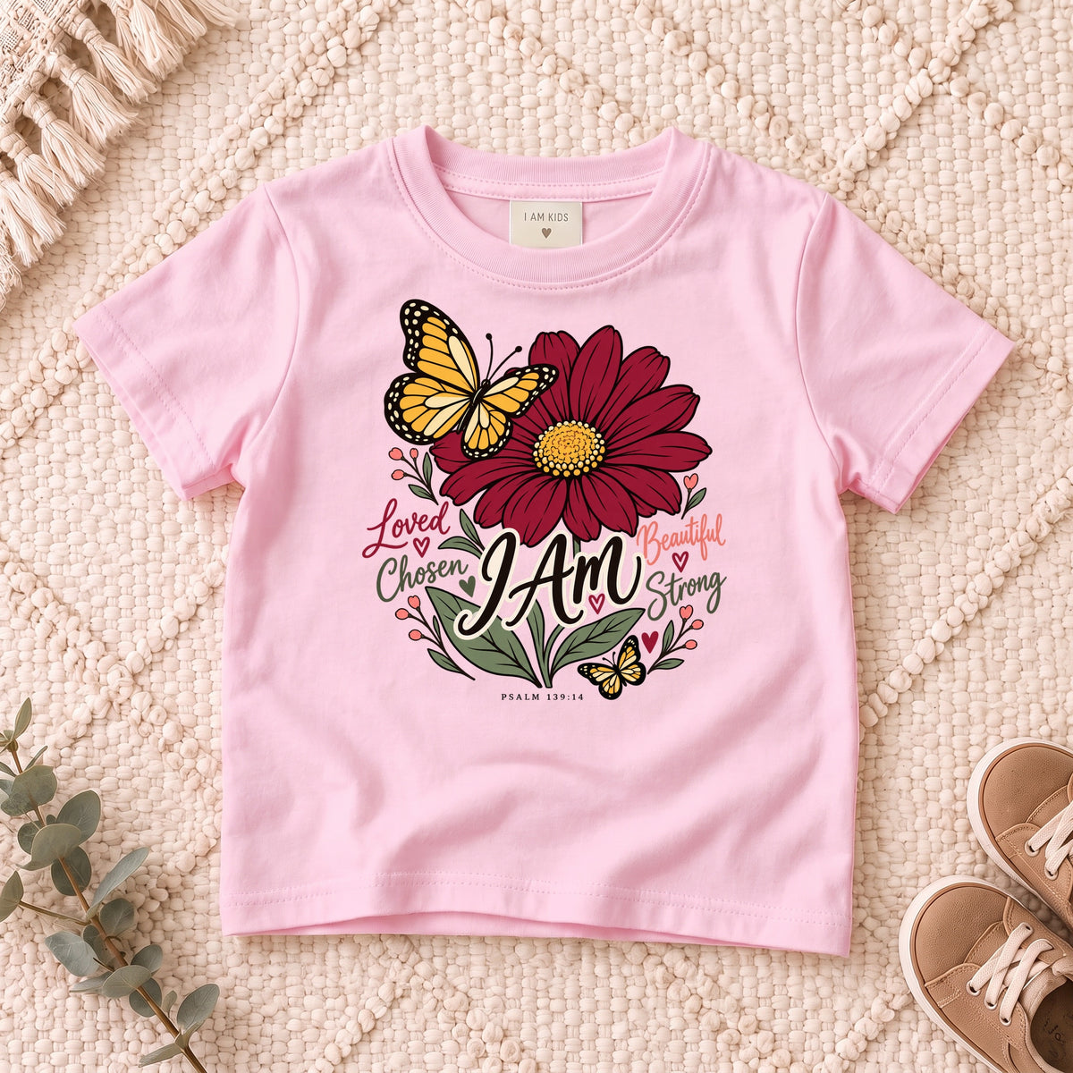 I AM Kids I AM Loved & Chosen Burgundy Flower Kids Tee | Psalm 139:14 design on a Light Pink shirt, shown on a cream rug.